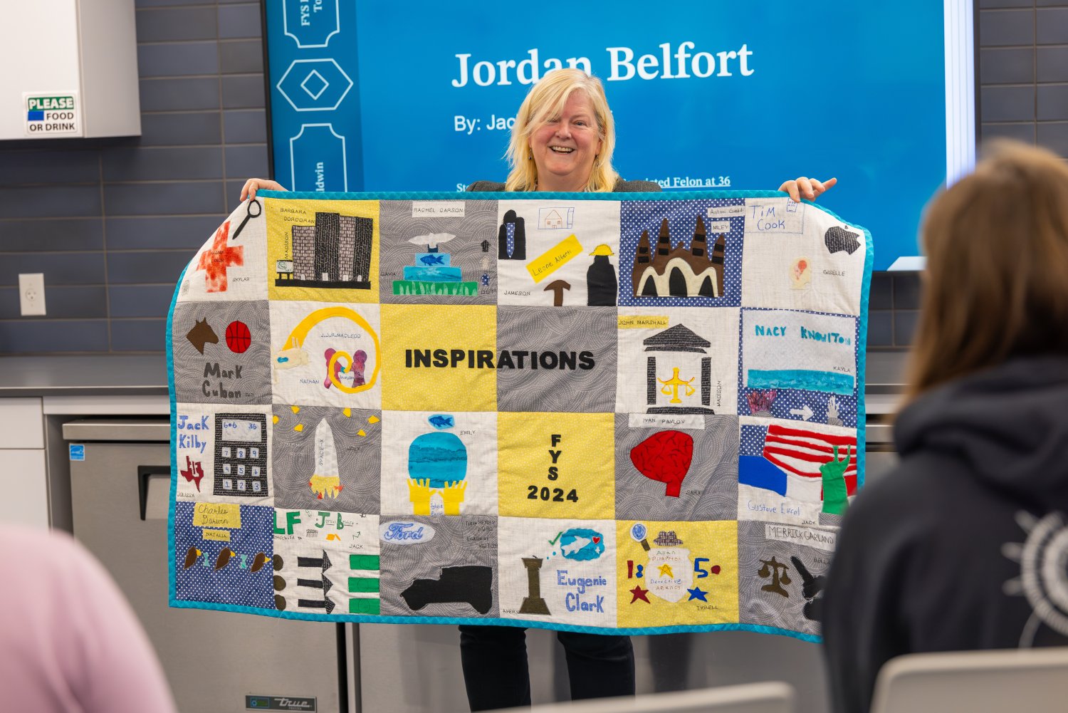 Professor Janet Baldwin showcases the collaborative quilt created by her First Year Seminar students.
