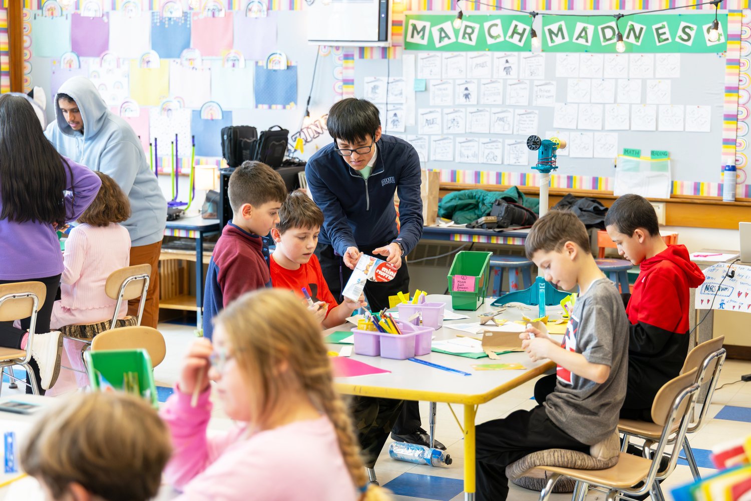 An RWU student guides fourth graders in designing cardboard wind turbine blades.