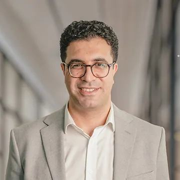 Headshot of Issa Ramaji, man with glasses and gray suit jacket. 