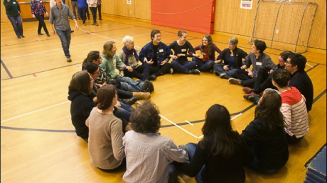 Training participants sit in a circle with linked arms.