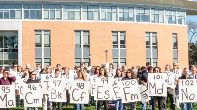 A group of people holding signs for the periodic table of elements.