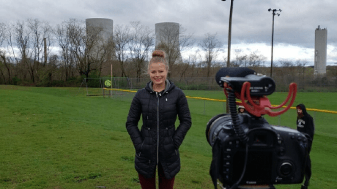 Person standing in grassy field looking at camera.