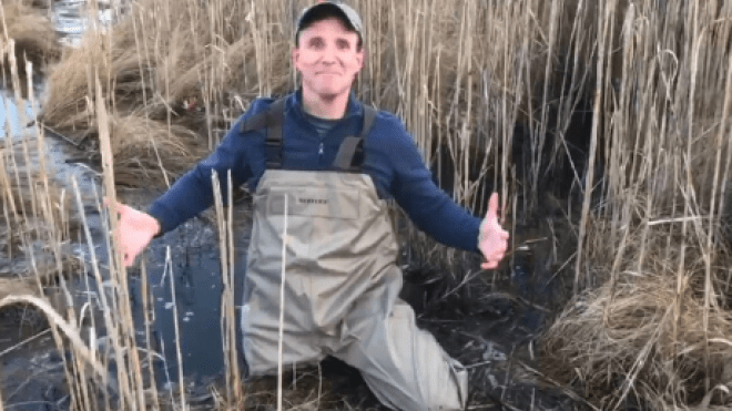 Person crouching in mud.