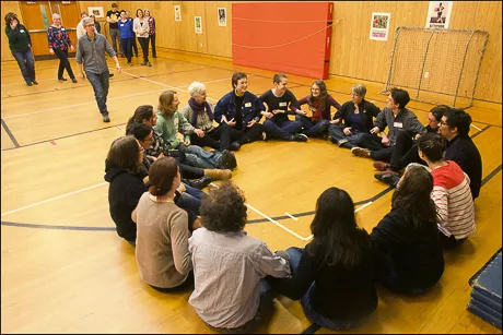 Training participants sit in a circle with linked arms.