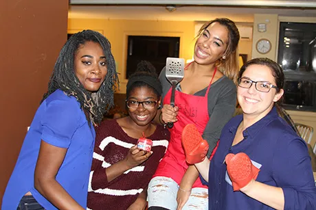Four students holding spatulas and smiling.