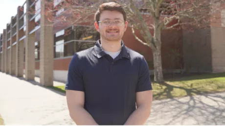 Sam Trieber standing in outside on a sunny day, smiling.