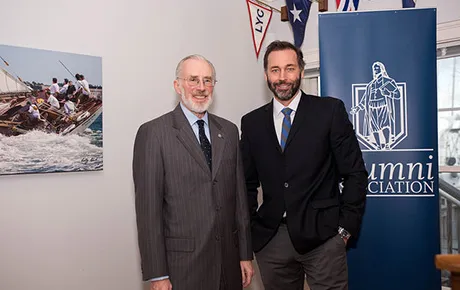 Two men stand near the alumni association banner.