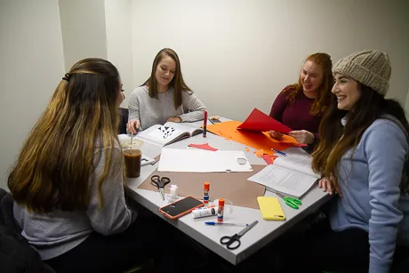 Students work on an art project around a table.