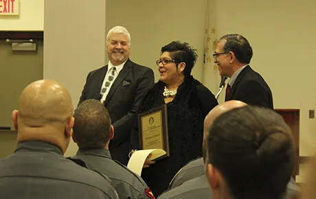 A woman and two men celebrate earning an award.