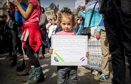 Refugee child holds up a book.