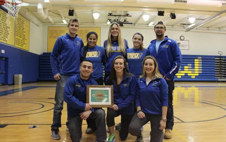 Student athletes and coaches hold their award.