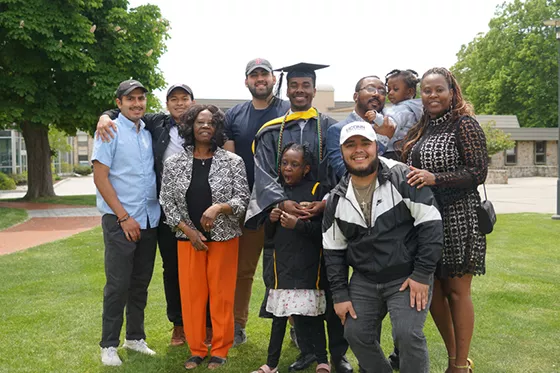 A graduating student stands with their family at commencement