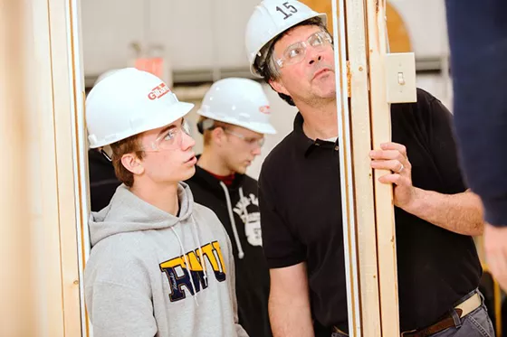 An instructor assisting a student on an electrical project.