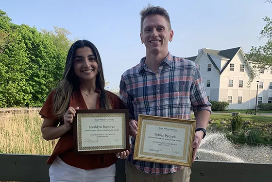 Two ANSOC graduates stand together holding certificates