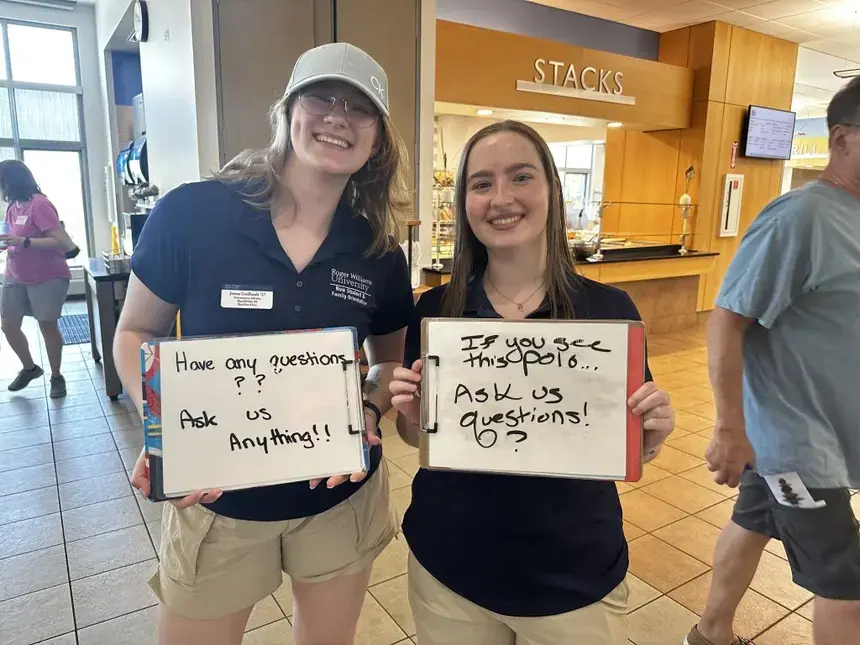 Two Orientation Advisors standing inside of Commons Dining Hall to help answer questions