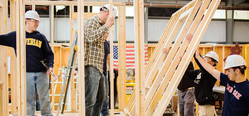 Construction students raise a building frame.