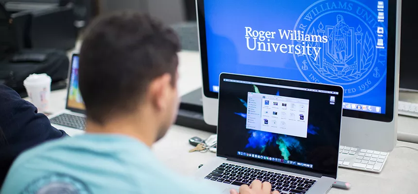 Student at computers, one displays RWU logo