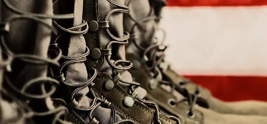 Army boots with an American flag in the background.
