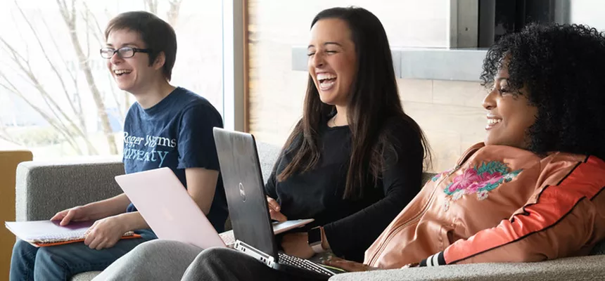 Students sit together with laptops laughing
