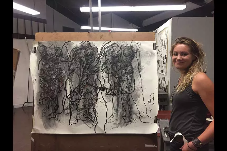A student standing next to her work.
