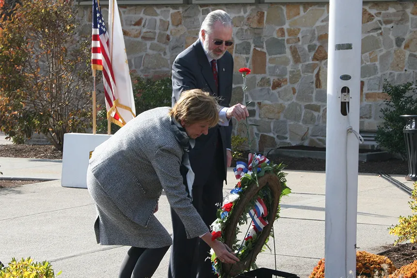 President and Maia Farish add a carnation to the wreath at the Memorial Day ceremony.