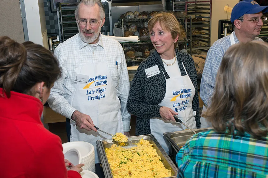 President and Maia Farish serve students during Late Night Breakfast.