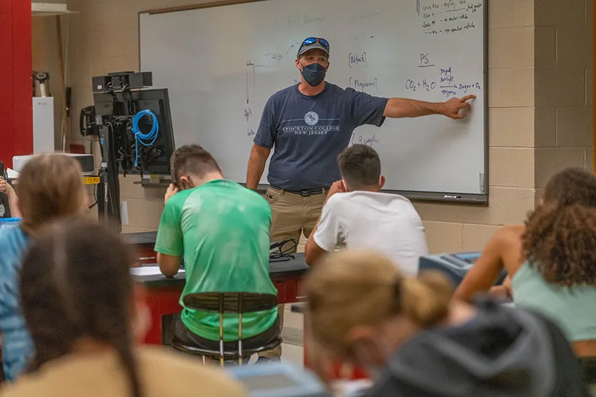 Brian Wysor talking to high school students in a Biology lab. 