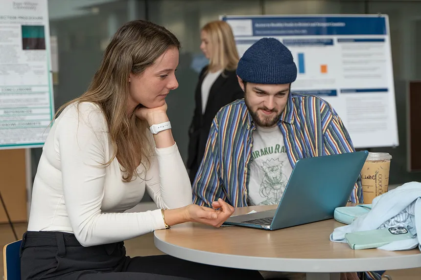 Two students looking a laptop screen in GHH. 