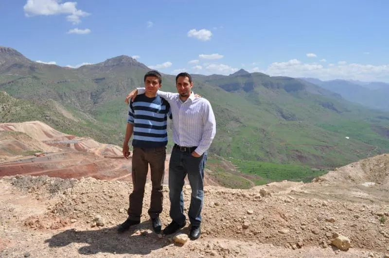Two people stand in front of mountains