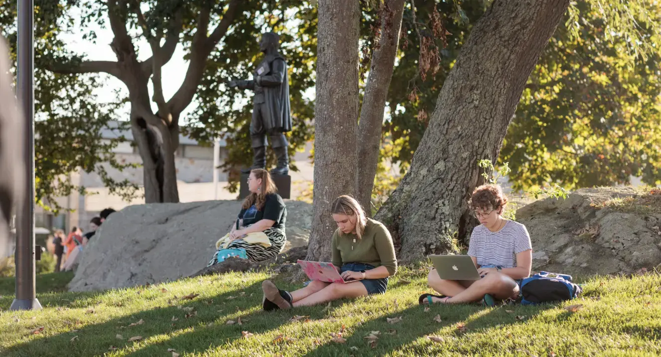 Students sitting on grass beside statue