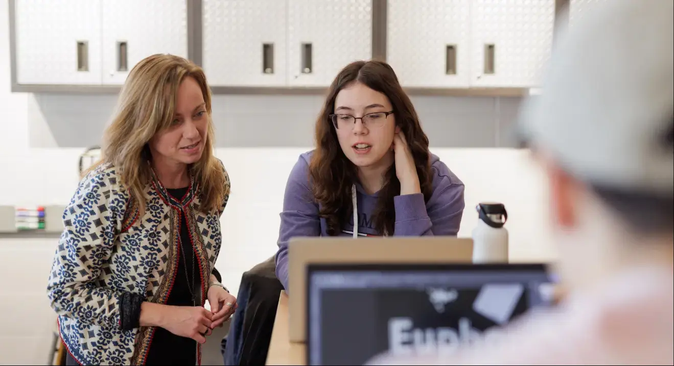 Professor helping students with a computer