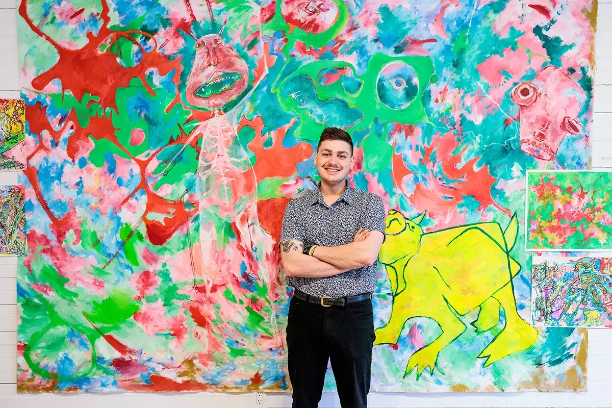 Student poses with large piece of artwork