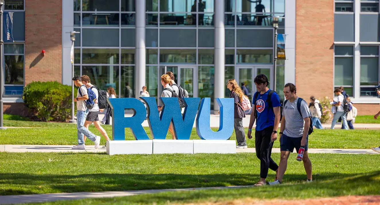 Students walk past RWU sign on campus