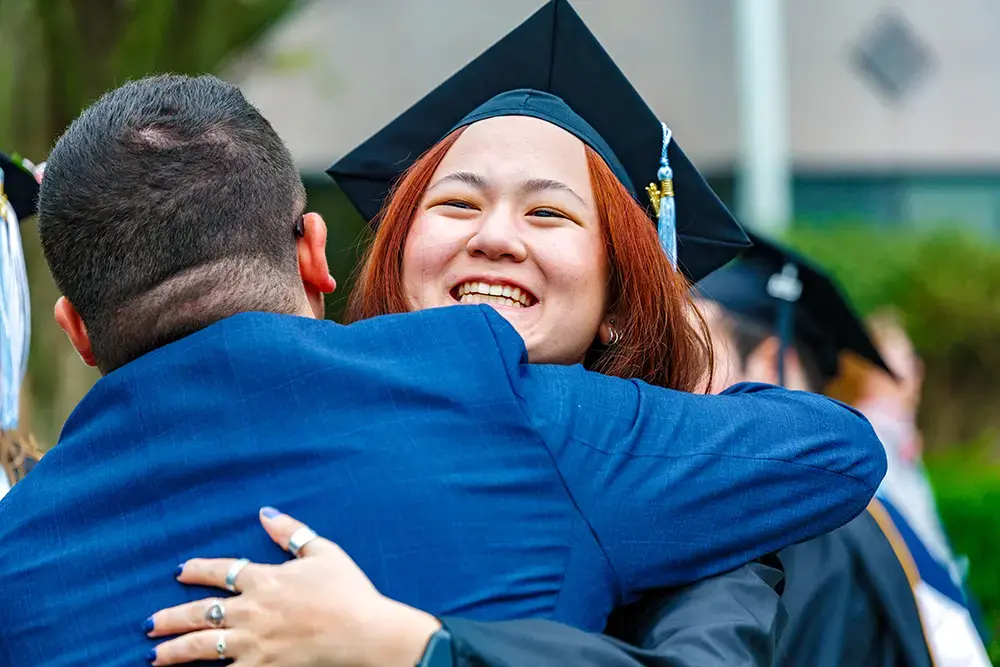 Graduate gives a hug to a family member at commencement